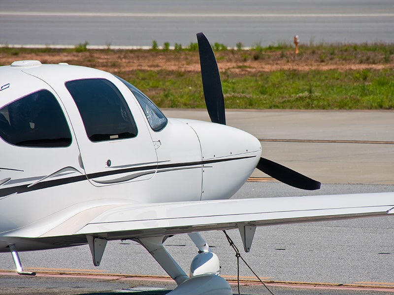A small private plane tied down next to the runway at a regional airport. A small private plane tied down next to the runway at a regional airport.