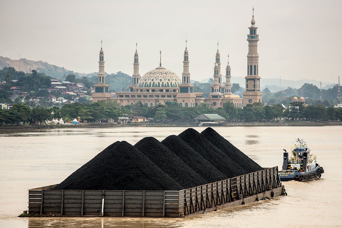 A tug pulls a coal barge past the Samarinda Islamic Center Mosque in East Kalimantan, Indonesia.