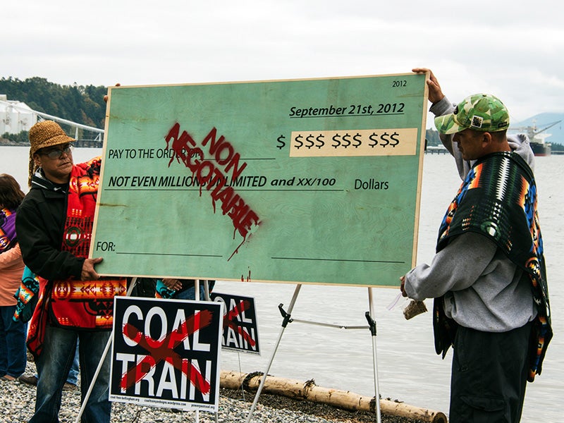 Lummi members hold a symbolic check burning protest to demonstrate that no amount of money can buy their support.