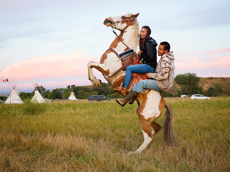 Stevana Salazar (left) of the Kickapoo Tribe of Texas rides with Arlo Standing Bear, Oglala Lakota from Allen, S.D., in the Sacred Stone Camp, Aug. 26, 2016.