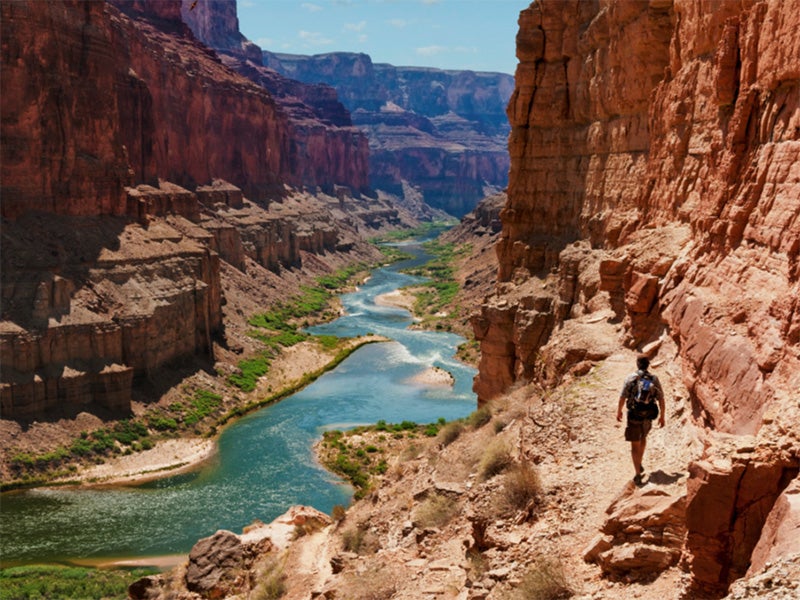 A hiker walks along the Colorado River. A hiker walks along the Colorado River.