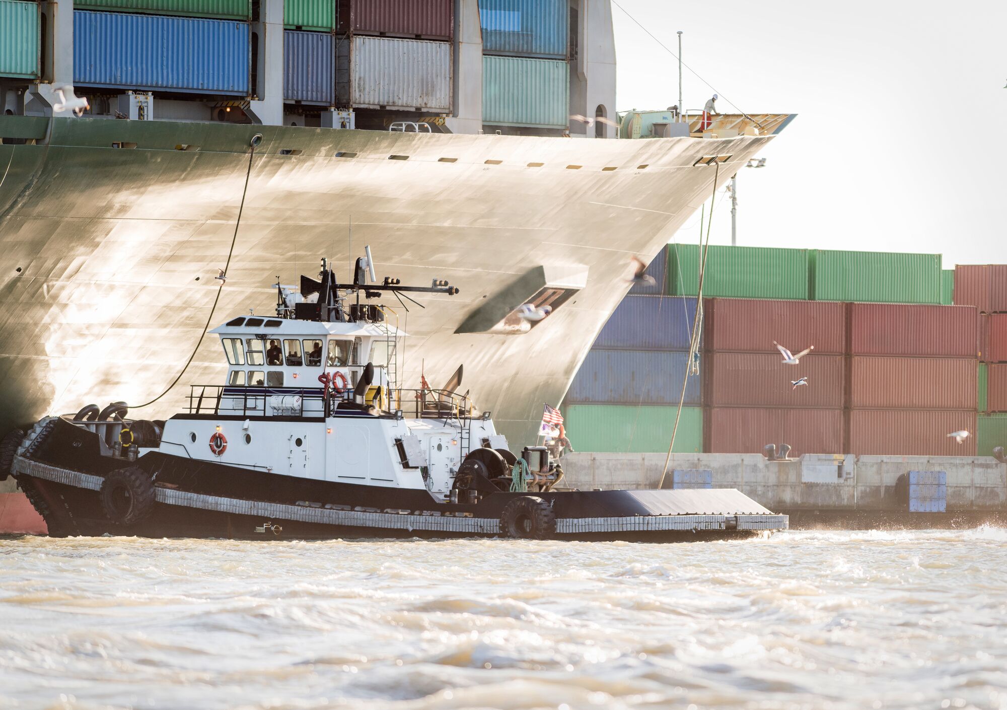 A tug boat helps a large container ship at the Port of Oakland in Oakland, California.