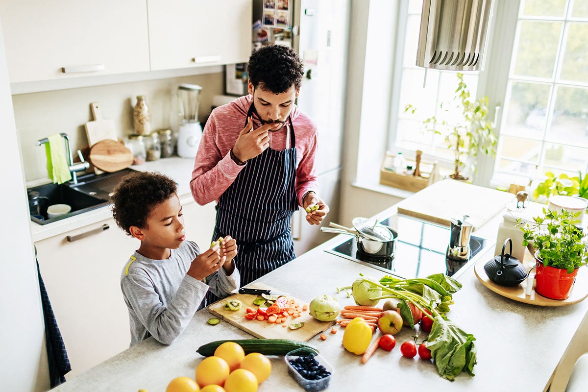 A father prepares a meal with his son on an induction stove. 