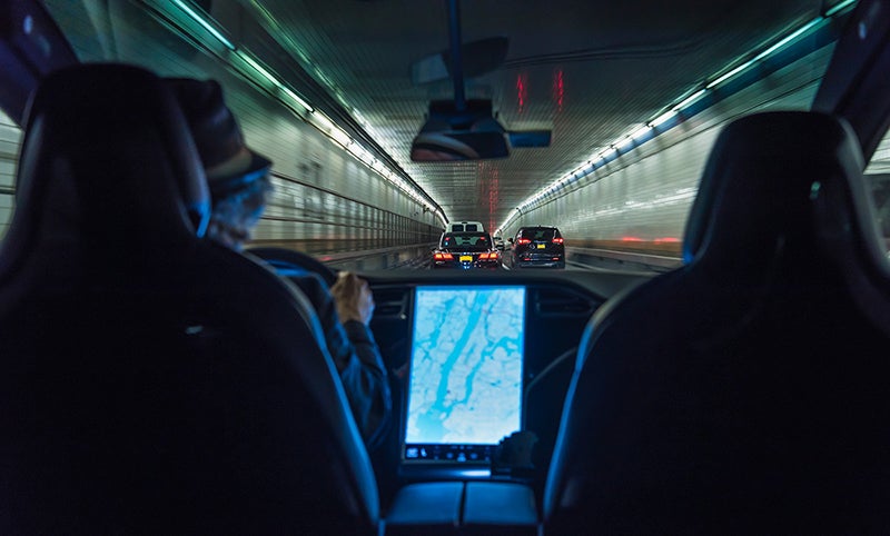 Photo from the perspective of a backseat passenger in an electric car driving through Holland Tunnel in New York City.