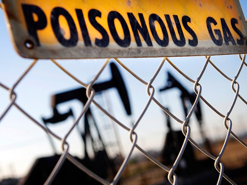 A sign hangs by the Inglewood Oil Field in Los Angeles, warning of hazardous fumes.