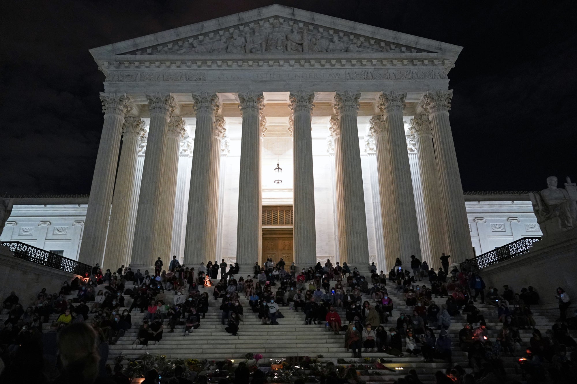 Photo of people gathered at a makeshift memorial for late Justice Ruth Bader Ginsburg on the steps of the Supreme Court building in Washington, D.C., on September 18, 2020.
