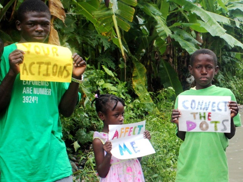 Children in Haiti hold up signs urging the international community to take action on climate change.