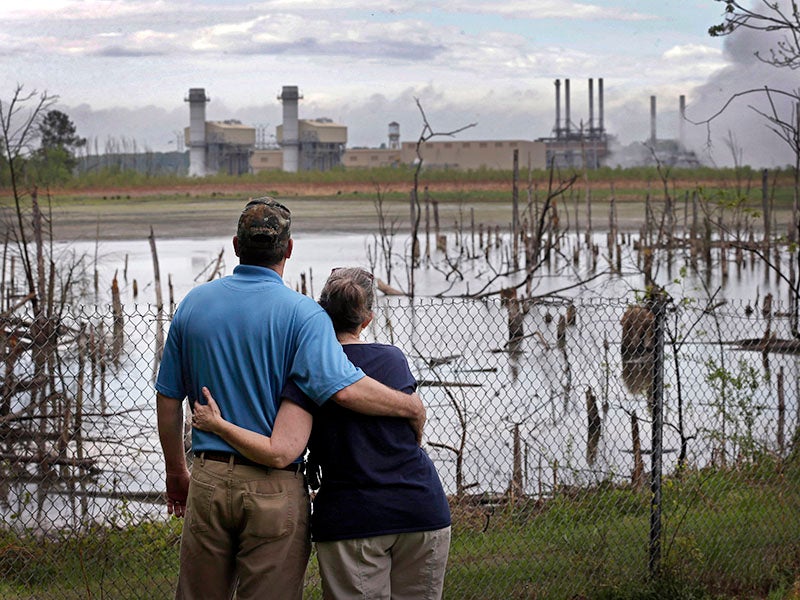 A couple in Dukeville, N.C., looks across a coal ash pond full of dead trees. 