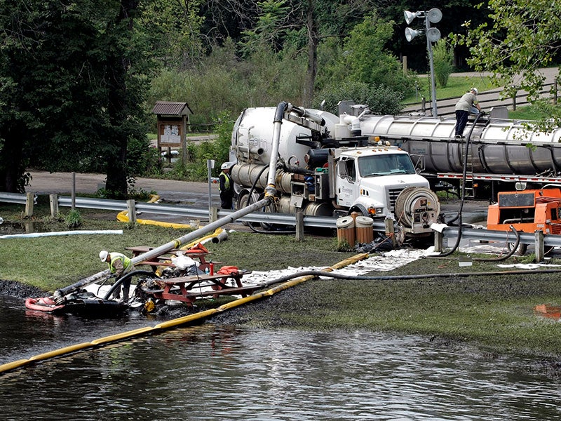 Workers using suction hoses try to clean up an oil spill of approximately 800,000 gallons of crude oil from the Kalamazoo River July 28, 2010 in Battle Creek, Michigan.