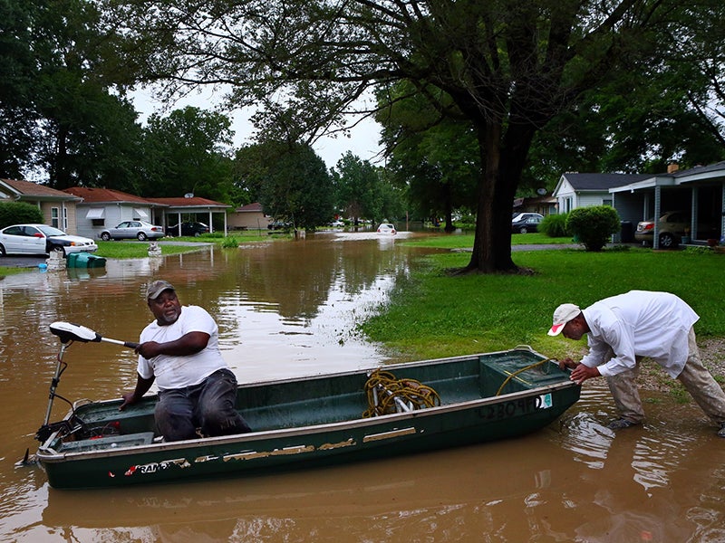 Danny Lane, right, gives his friend Walter Byrd a push as Byrd prepares to head down a flooded Centreville street in June 2015. Firefighters evacuated residents earlier in the day.