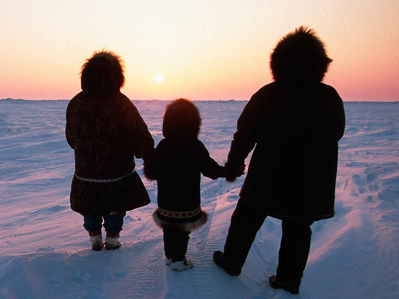 Family framed against the sunset, in the Arctic. (Jeff Schultz / National Geographic Creative)