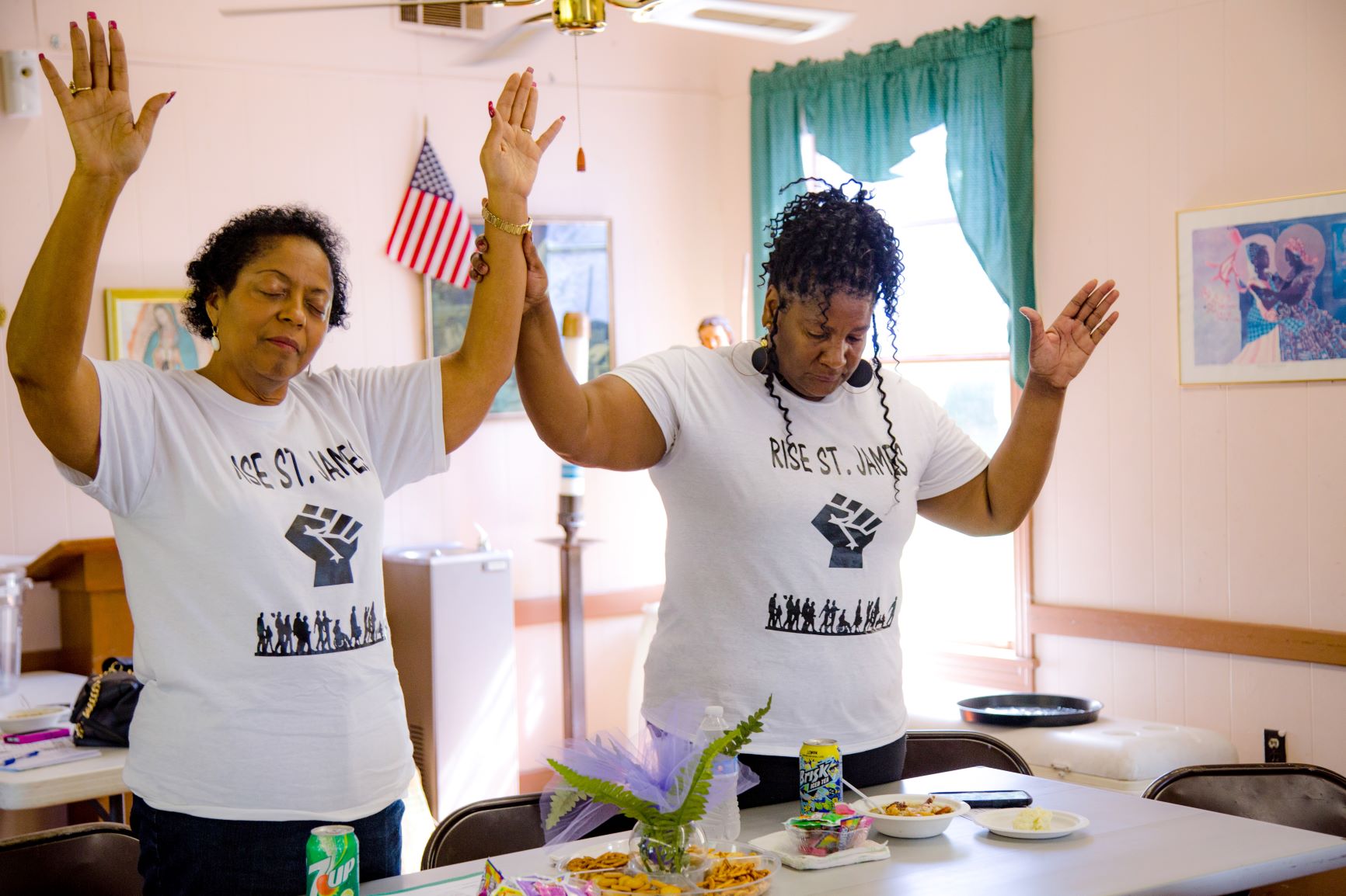 Sharon Lavigne (left), founder of RISE St. James, joins another activist in a moment of prayer at a community meeting in 2019.