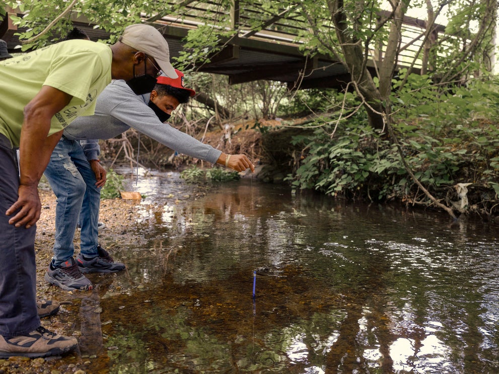 Dennis Chestnut teaches his grandson, Horus Plaza, how to test the water quality of the Watts Branch of the Anacostia River in Marvin Gaye Park in Washington, D.C. in May 2021.
(Jared Soares for Earthjustice)