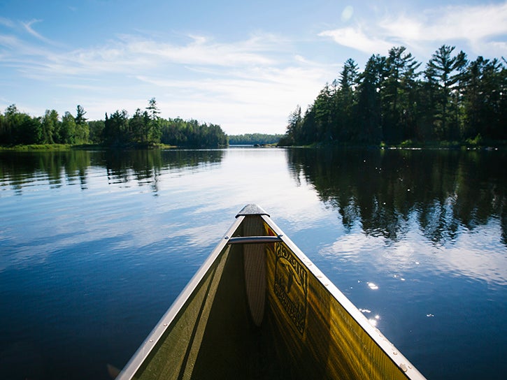 Canoeing over glassy water in the Boundary Waters Canoe Area Wilderness.