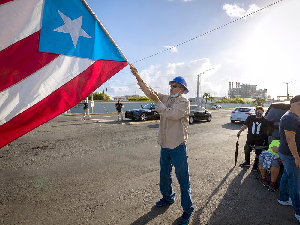 A protester waves the Puerto Rican flag during a public protest against the privatization of the electric power service in San Juan, Puerto Rico, in June 2021.