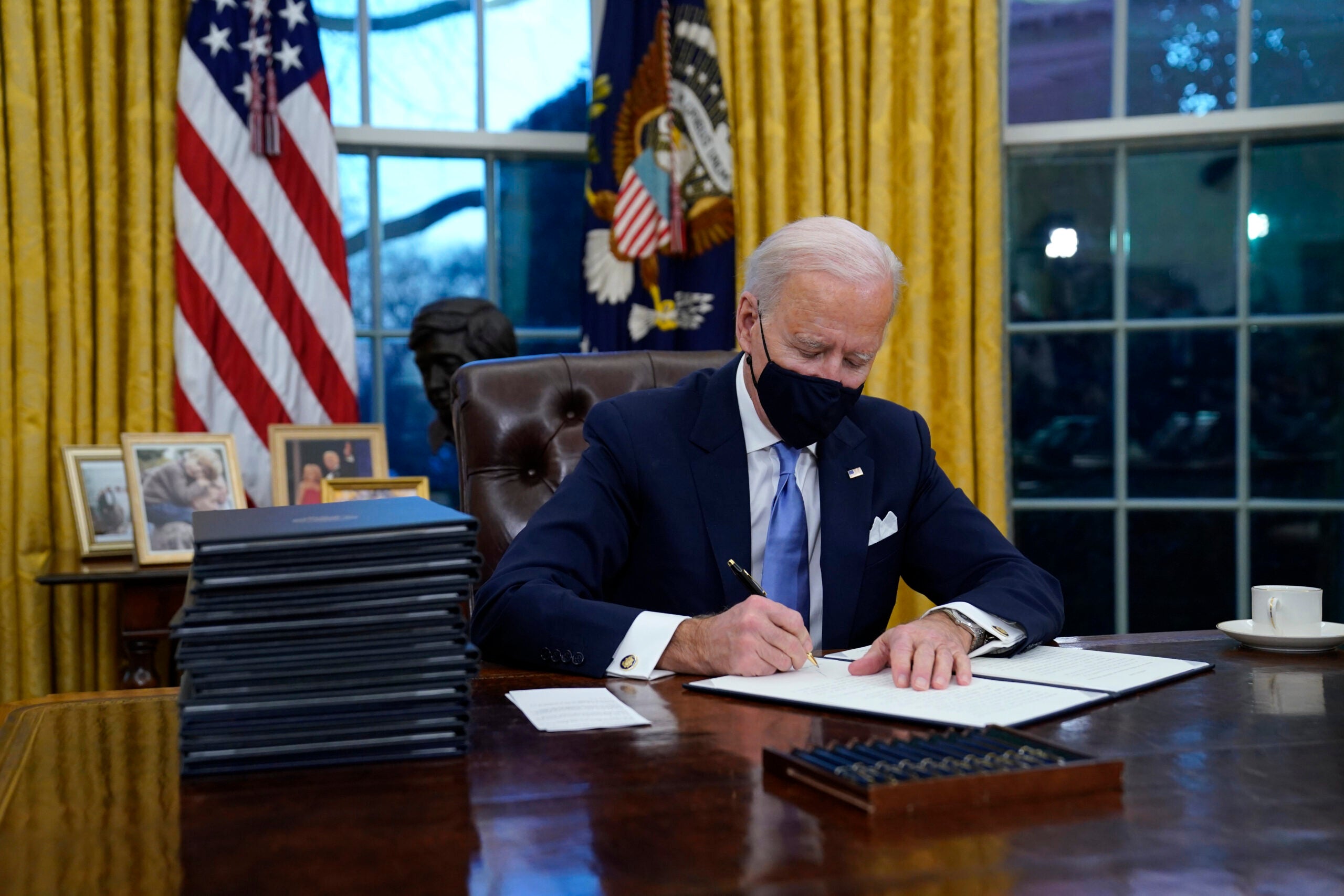 Joe Biden signs his first executive orders in the Oval Office on day one of his administration, January 20, 2021.