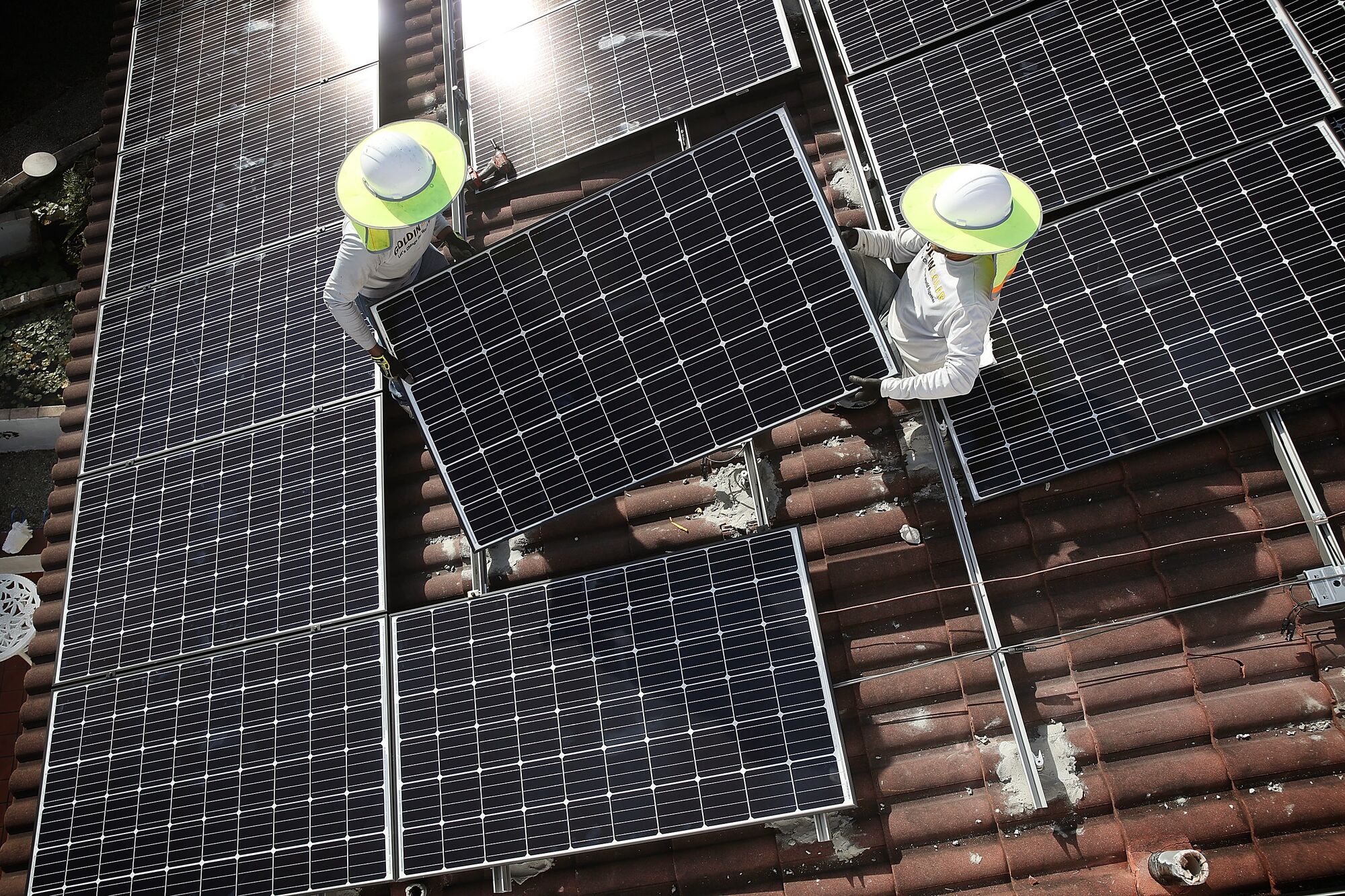 Aerial view of technicians installing a solar panel system on the roof of a home in Palmetto Bay, Florida. (Joe Raedle / Getty Images)