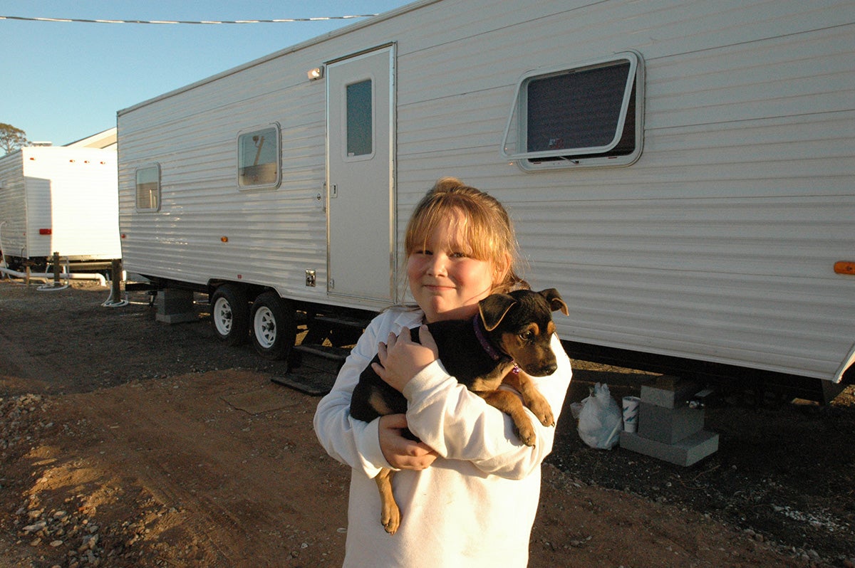 Brianna, a Mississippi resident, and her new dog Dixie in front of the travel trailer that served as their family's temporary home in November 2005. (Mark Wolfe / FEMA)
