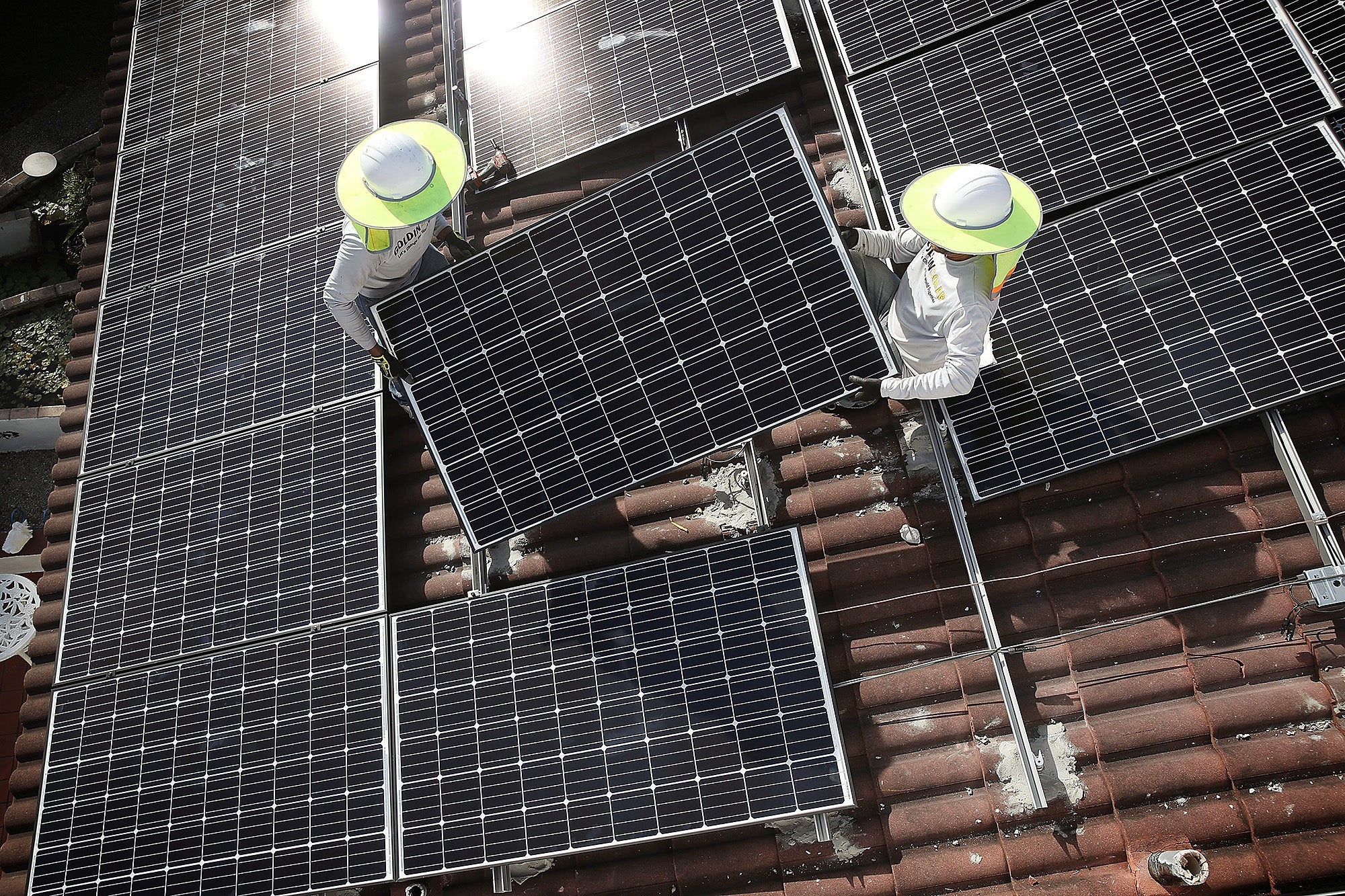 Two men install a solar panel system on the roof of a home. Solar energy is one way we can transition to a 100% clean energy economy.