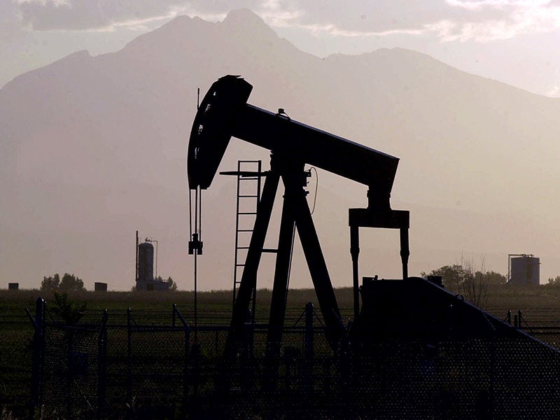 An oil pumper is silhouetted against Long's Peak near Firestone, Colo.