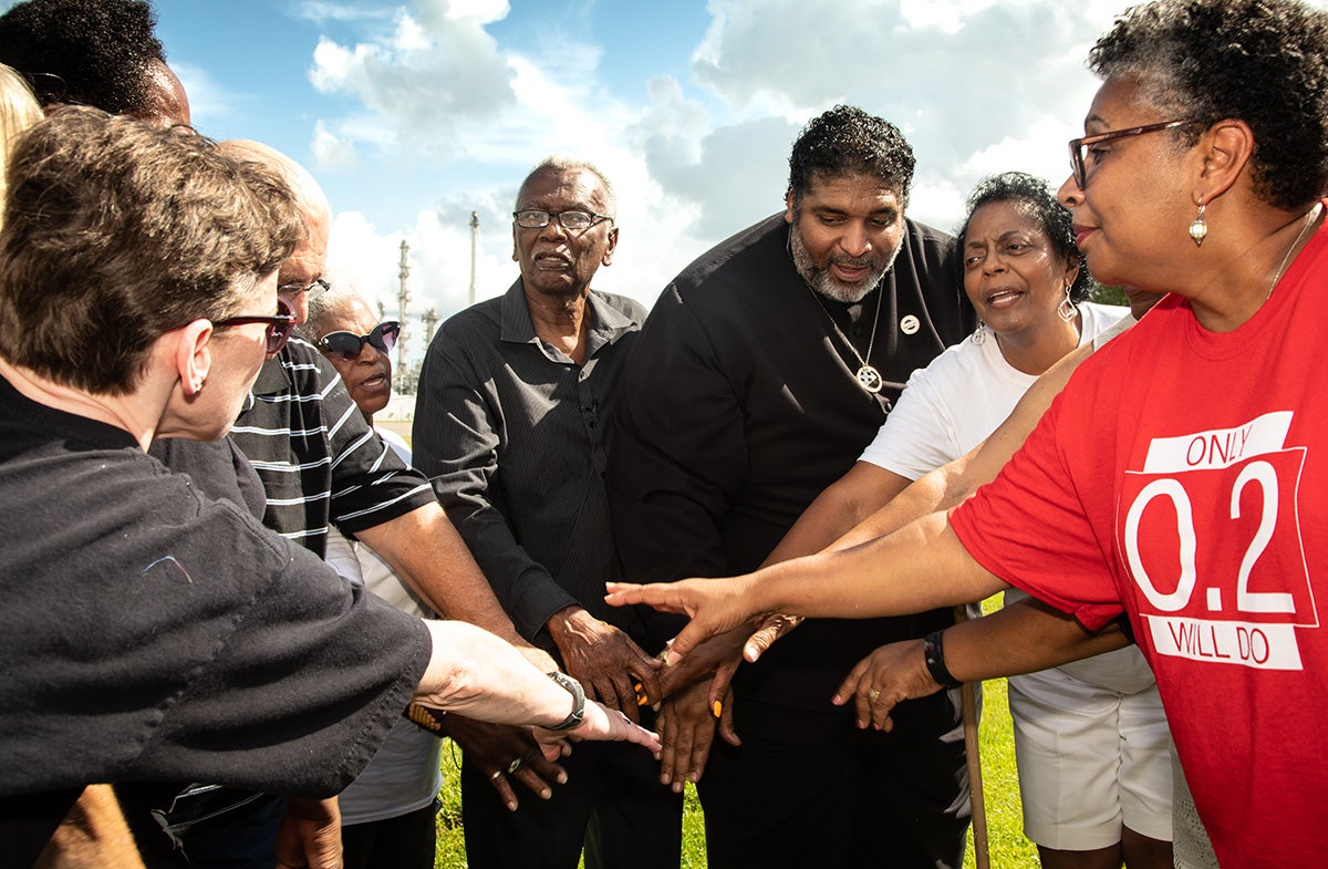 Robert Taylor, Rev. William J. Barber II, and Sharon Lavigne, founder of Rise St. James, gather in front of the Denka/DuPont plant with members of the Black and white community who live in “Cancer Alley.”