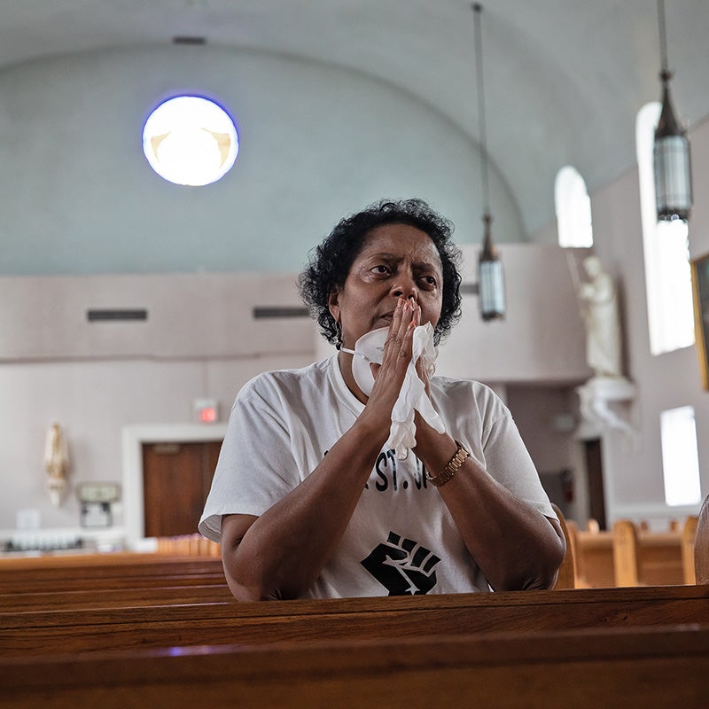 Sharon Lavigne kneels and prays in the pews of a house of worship.