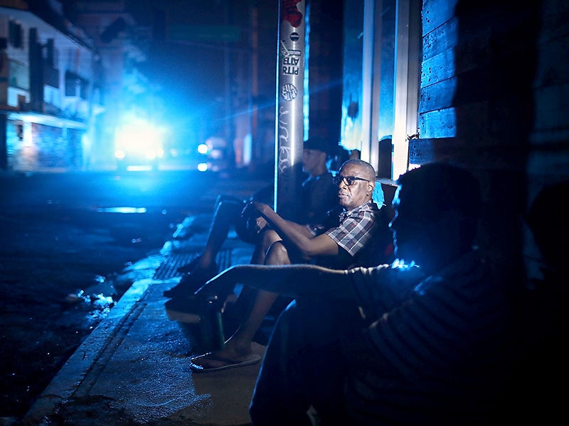 San Juan resident Jaime Degraff sits on a dark curbside with his neighbors, waiting for the city's electrical grid to be fixed after Hurricane Maria ravaged Puerto Rico on September 23, 2017.
