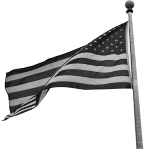 Black and white image of the United States flag, flying at the top of a flag pole in a slight breeze.