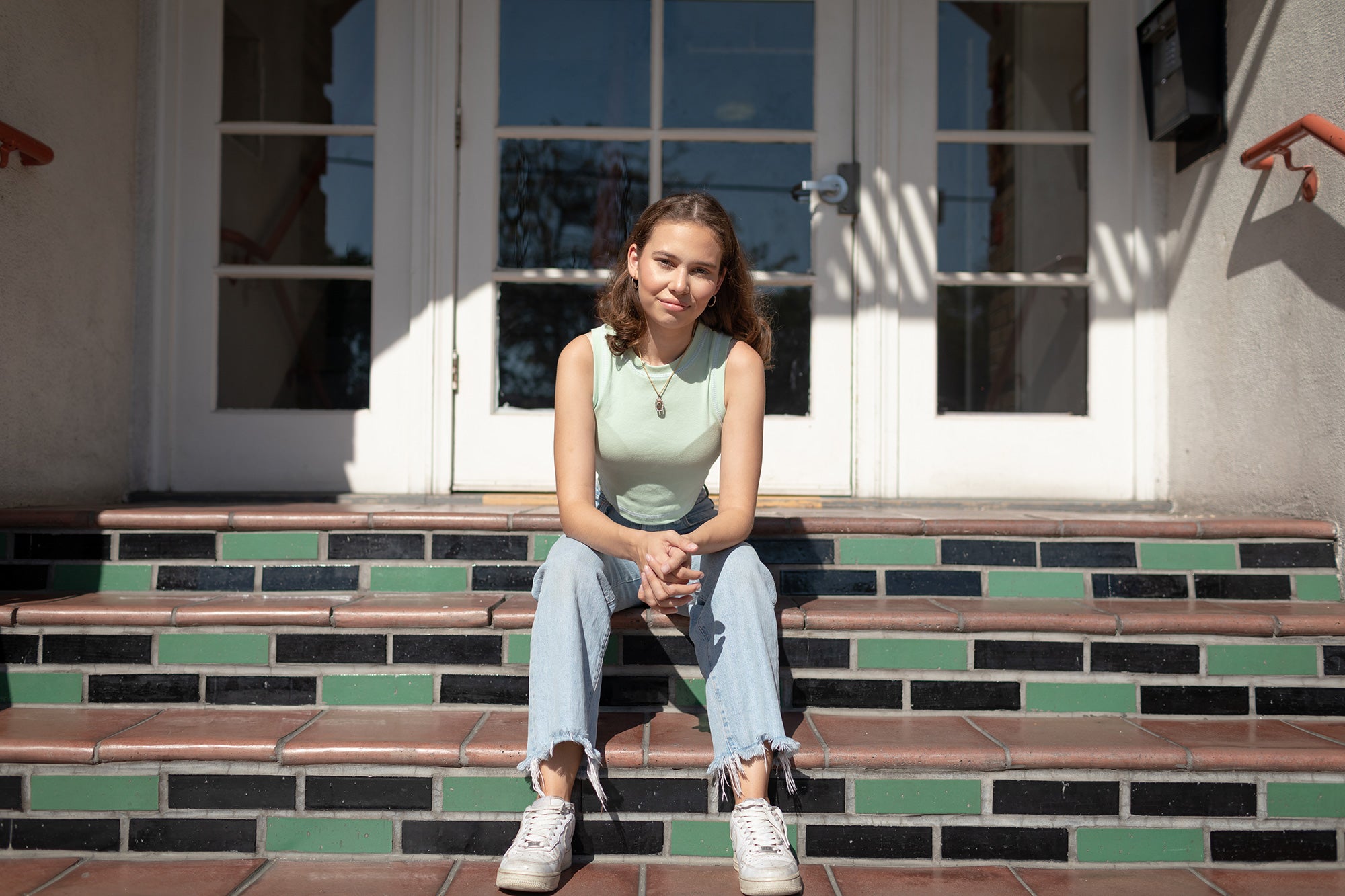 Nalleli Cobo sits at the Los Angeles apartment complex where she grew up, directly across the street from the now closed AllenCo Energy site.
