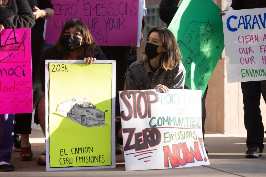 Alejandra Ruedas, right, holds a sign at a rally before a California Air Resources Board public hearing to consider proposed Advanced Clean Fleets Regulation on Oct. 27, 2022, in Sacramento, Calif. (Chris Jordan-Bloch / Earthjustice) 