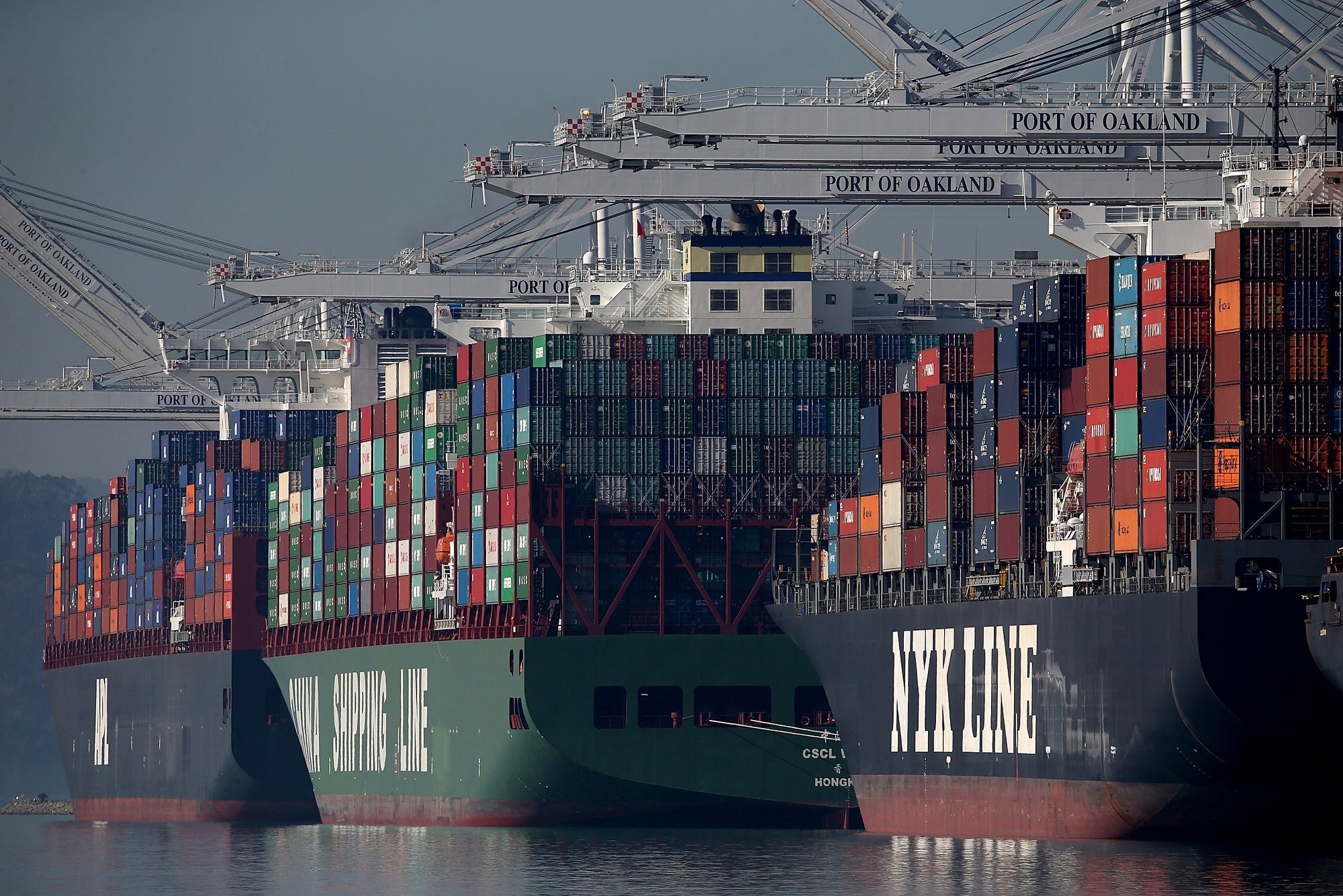 Three large container ships next to each other, stacked with containers.
