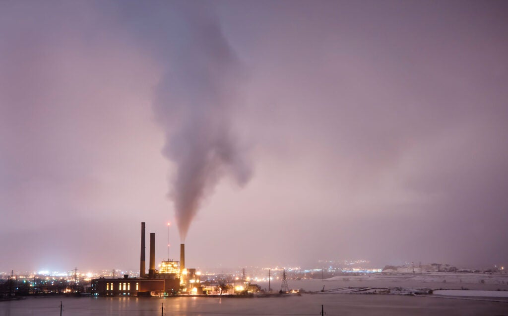 Smokestack of Valmont Power Station in Boulder, Colo., emits a plume of smoke into a hazy, darkened sky.