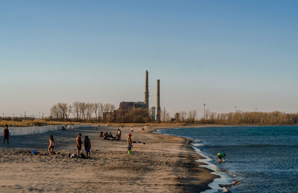 The now-closed Waukegan Generating Station, on the shore of Lake Michigan in Waukegan, Ill. Beachgoers picnic and play on the sandy shore.