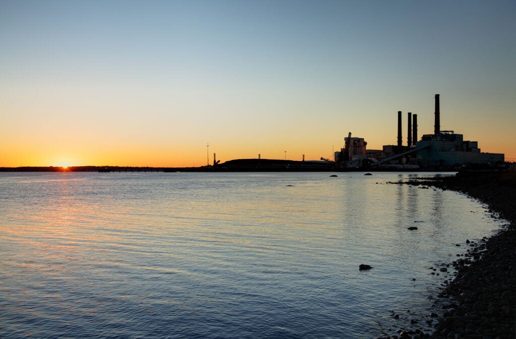 The sun peeks over the horizon next to the Brayton Point Power Station in Somerset, Mass., in 2012.