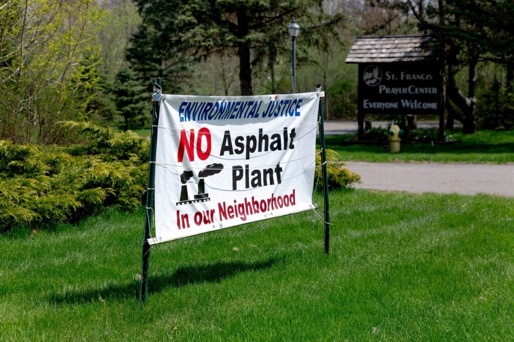 A sign protesting the asphalt plant is seen outside of St. Francis Prayer Center on May 10, 2022 in Flint, Michigan. (Sylvia Jarrus for Earthjustice)