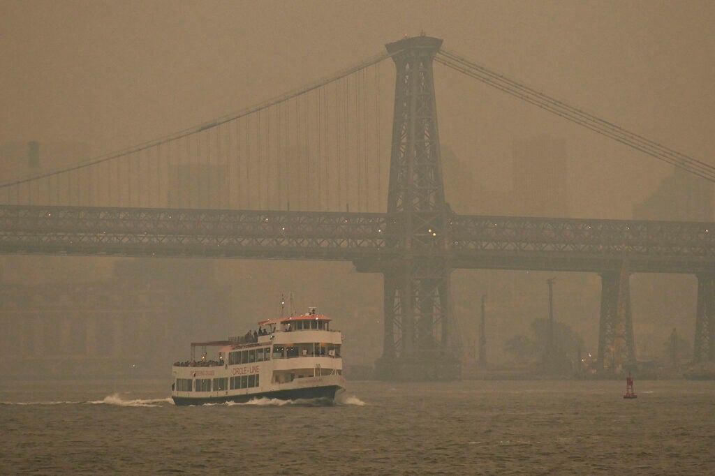 A Circle Line ferry sails past the Williamsburg Bridge as the Manhattan skyline is shrouded in smoke from Canada wildfires on June 6, 2023 in New York City. New York City is bathed in a blanket of unhealthy air as smoke from Canadian wildfires seeps across much of the eastern U.S. and Great Lakes areas. (NDZ/STAR MAX/IPx via AP)