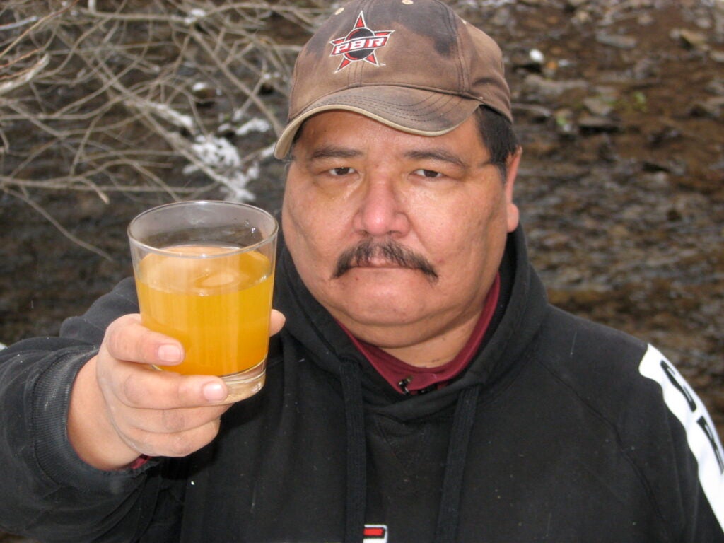 Dean Stiffarm of Fort Belknap, Mont., holds a glass of water contaminated by the Zortman-Landusky mines. (Earthworks)