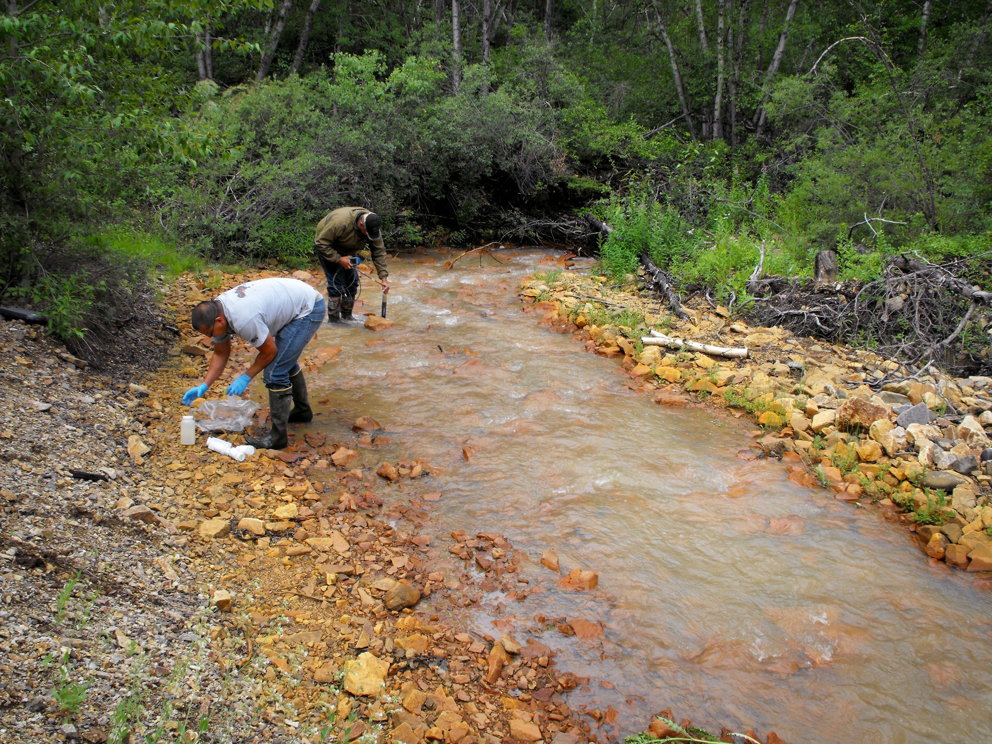 Two men taking water samples in a mountain creek