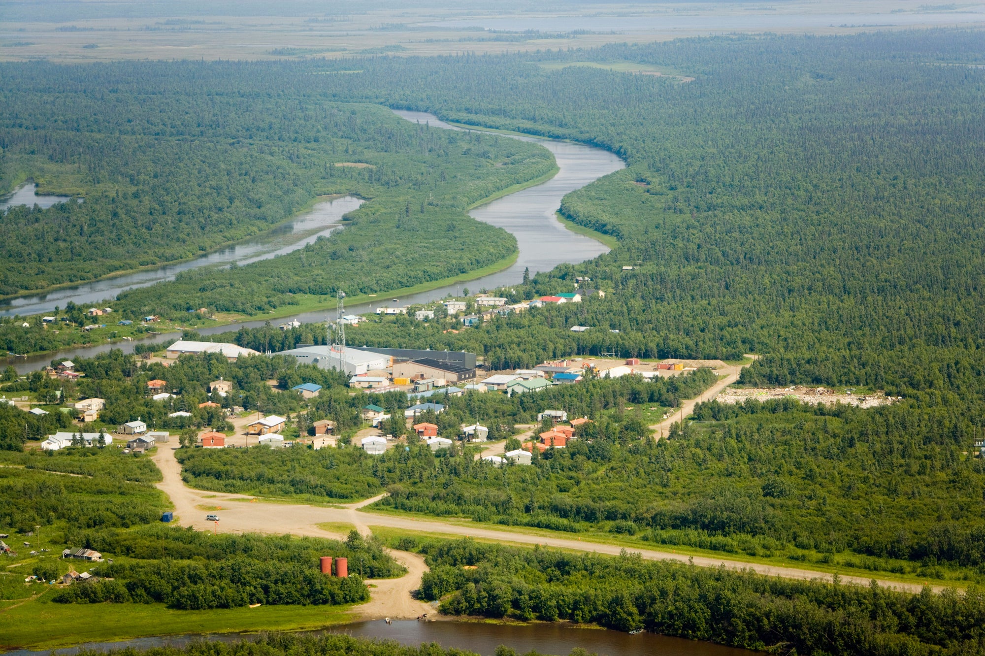 A small village surrounded by green trees and a river.