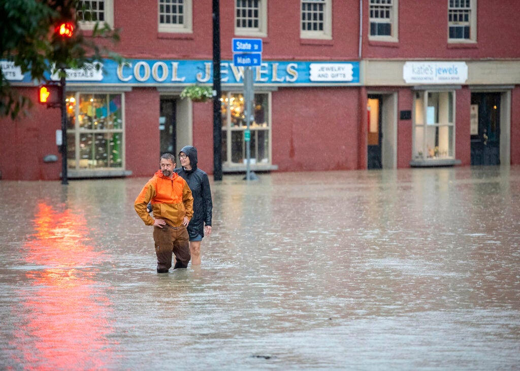 Montpelier resident Ben Cheney and a companion survey rising floodwaters at the intersection of State and Main streets in downtown Montpelier, Vermont, on July 10, 2023. (Jeb Wallace-Brodeur / The Times Argus via AP)