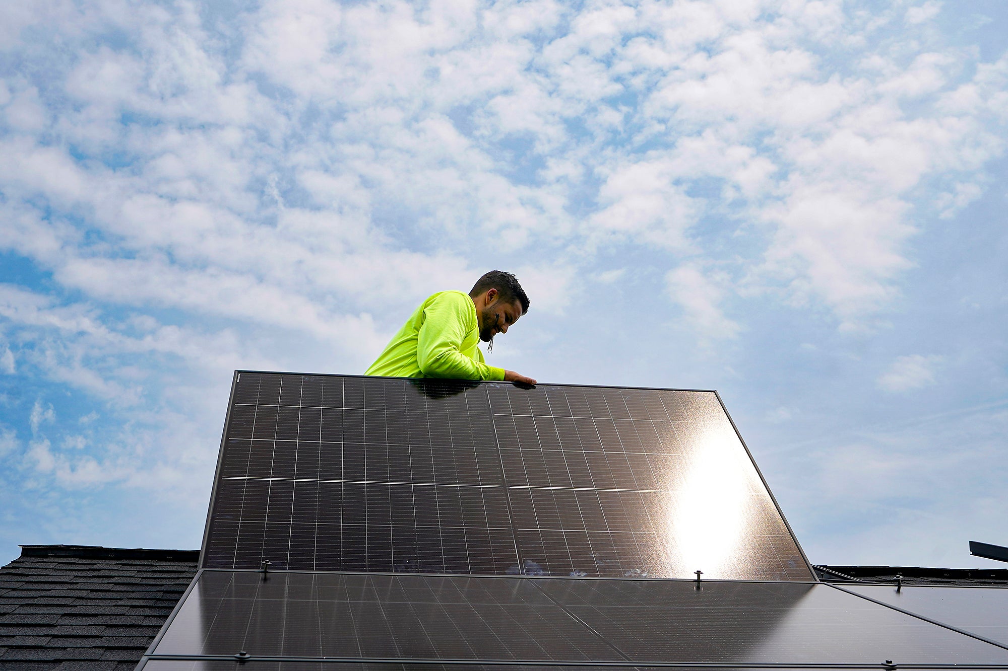 Man on roof putting a solar panel in place