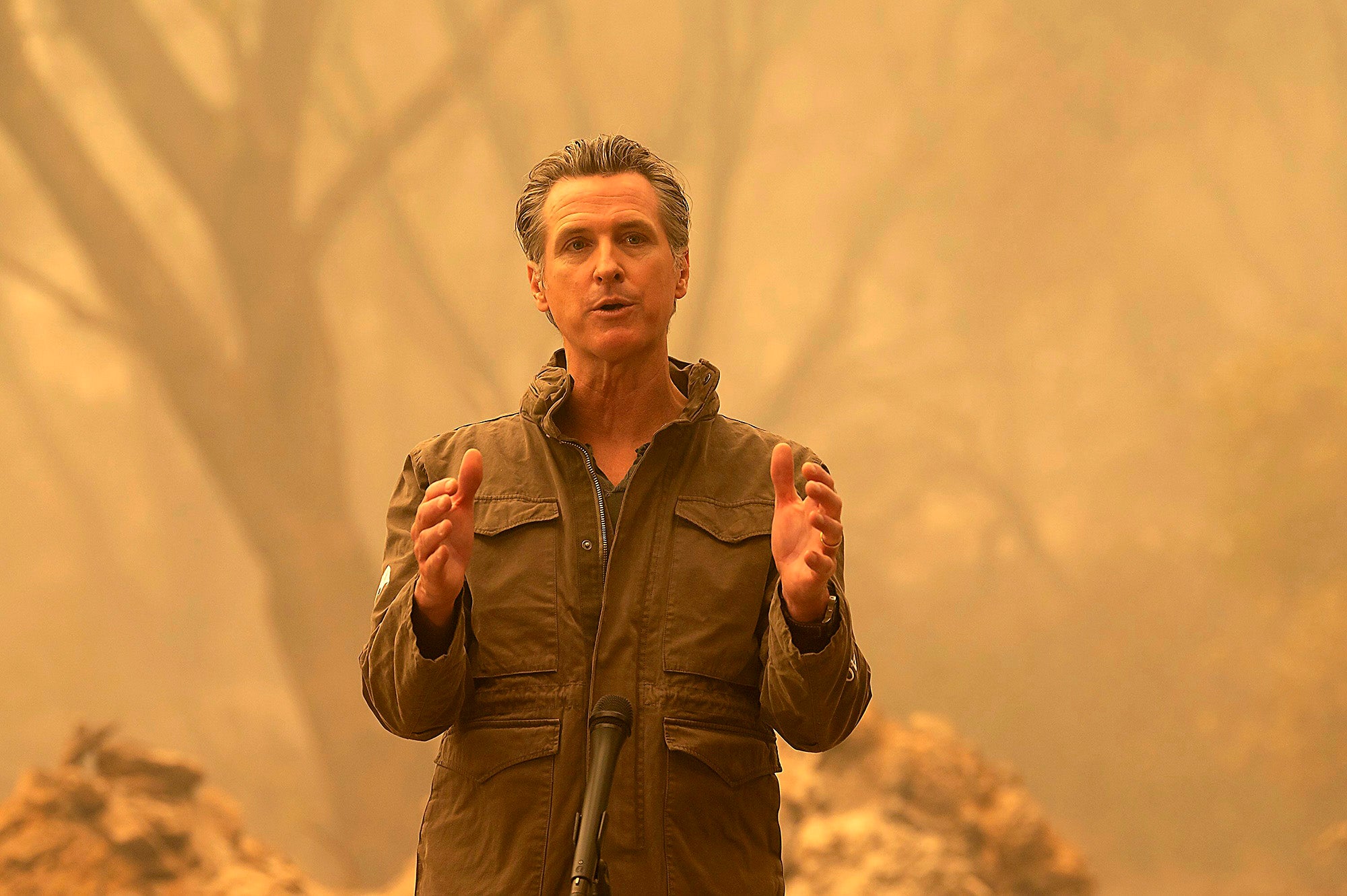 Gavin Newsom speaking in a burned and smokey area.