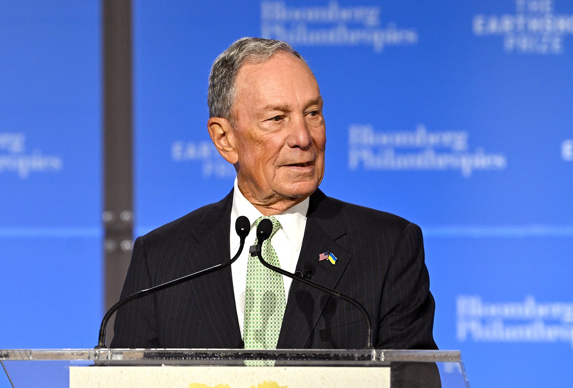 Michael R. Bloomberg speaks onstage at a podium with a blue background