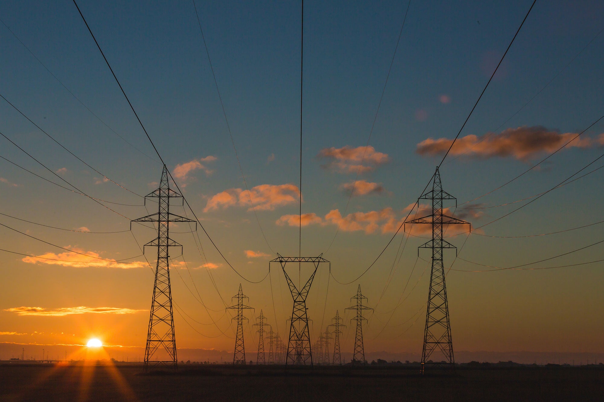 Power lines recede into the horizon as the sun sets.