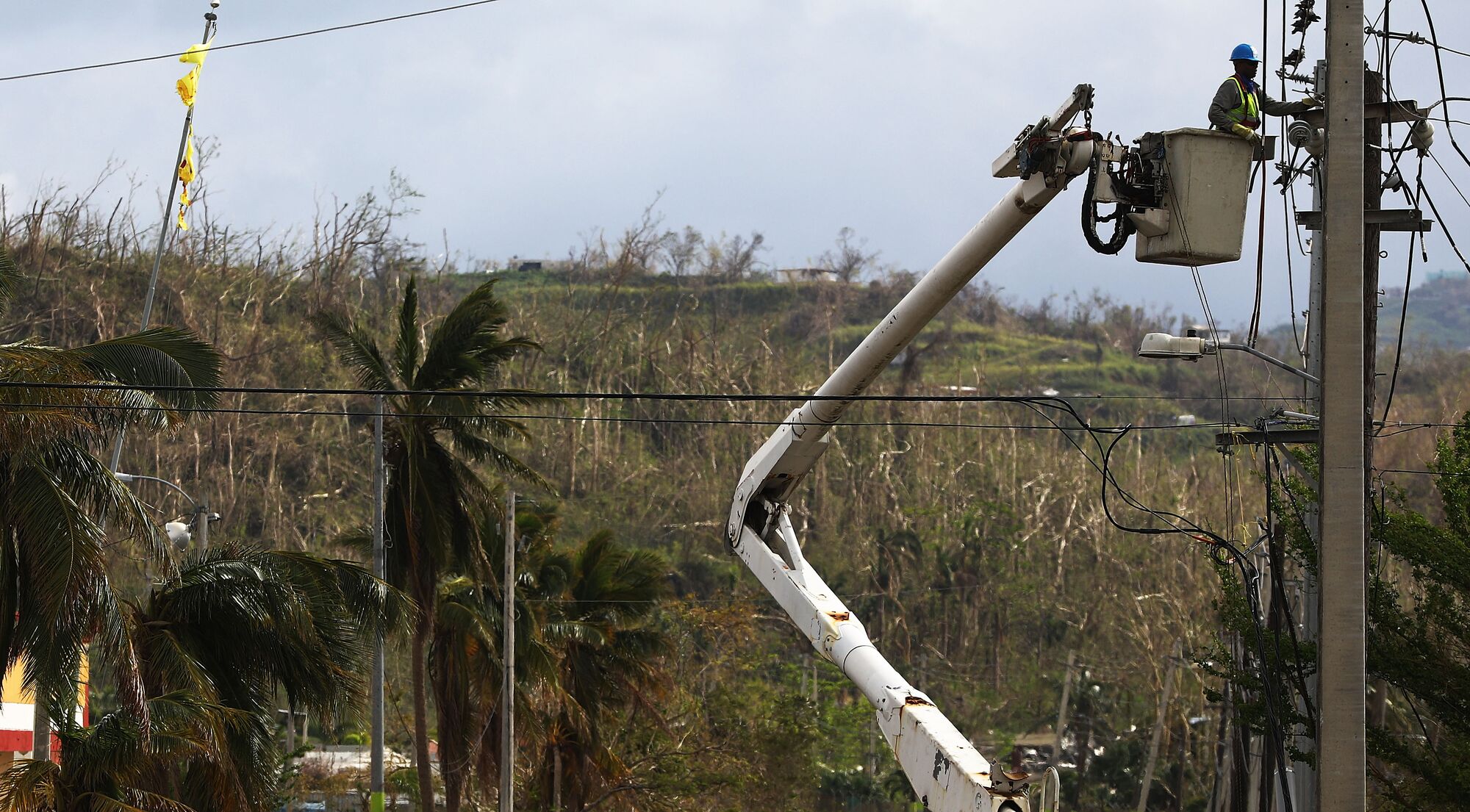 Un empleado repara líneas eléctricas aproximadamente dos semanas después de que el huracán María arrasara el archipiélago el 5 de octubre de 2017 en San Isidro, Puerto Rico.