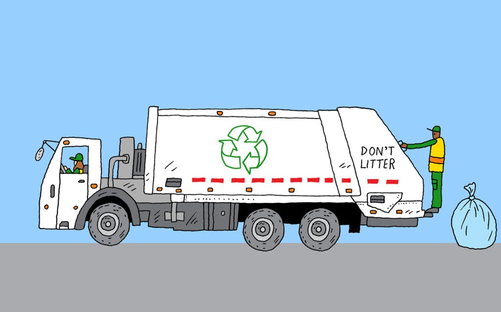 A sanitation worker tosses a bag of recycling into an electric sanitation truck.