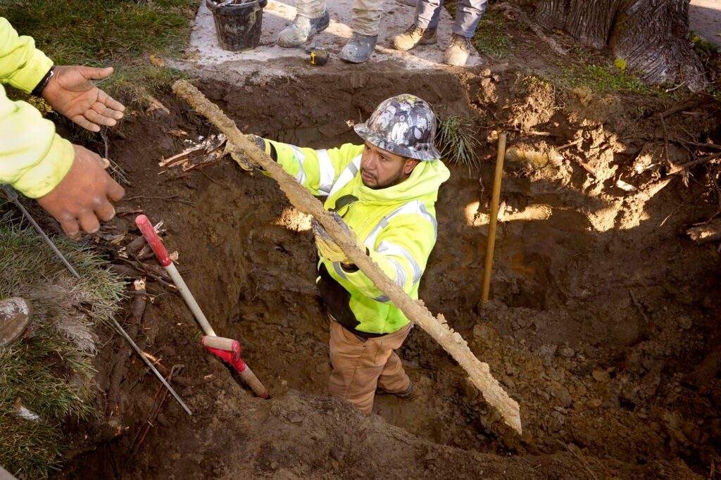 A cut lead pipe is pulled from a dig site for testing at a home in Royal Oak, Mich., on Nov. 16, 2021. (Carlos Osorio / AP)