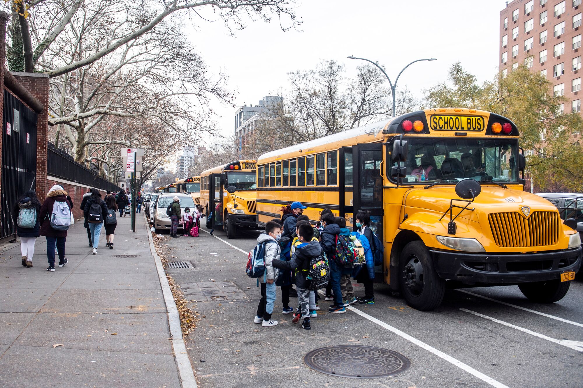 Students board a school bus outside New Explorations into Science, Technology and Math (NEST+m) school on the Lower East Side neighborhood of Manhattan on Tuesday, Dec. 21, 2021, in New York.