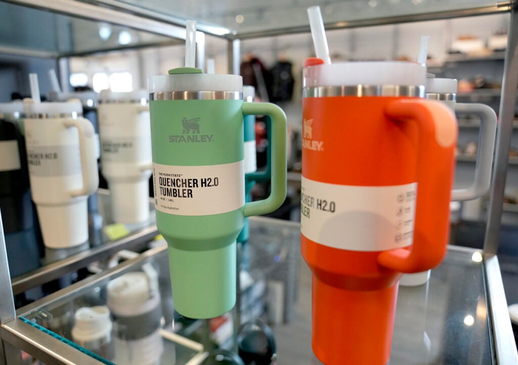 Colorful insulated cups with handles and straws on a shelf in a store.