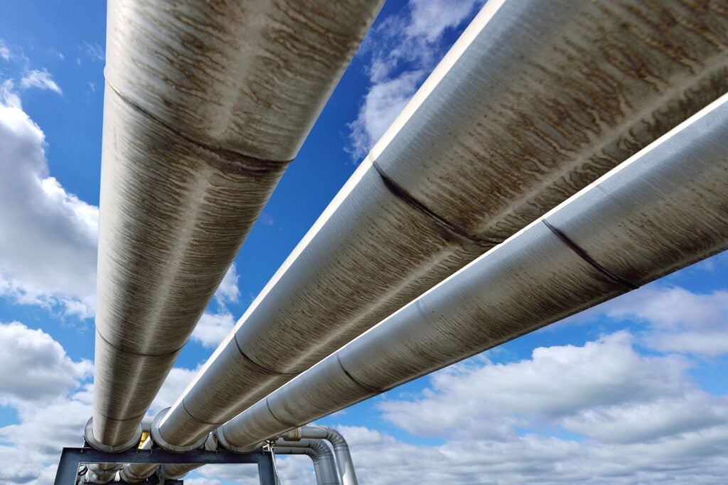 Three pipelines under a blue sky with puffy white clouds.